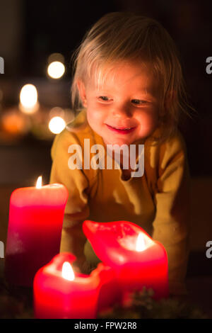 Tout-petit à la recherche à l'avènement des bougies à l'époque de Noël Banque D'Images