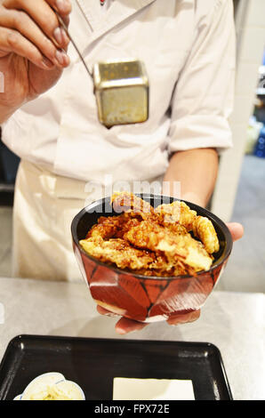 Chef pouring sauce soja Tempura sur bol de riz Banque D'Images