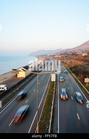 Conduite le long de la côte nord du Pays de Galles A55 Road dans la lumière du soir. Banque D'Images