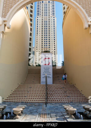 Femme descendant des escaliers du centre commercial de la promenade dans le quartier du port de plaisance de Dubaï, Émirats Arabes Unis Banque D'Images