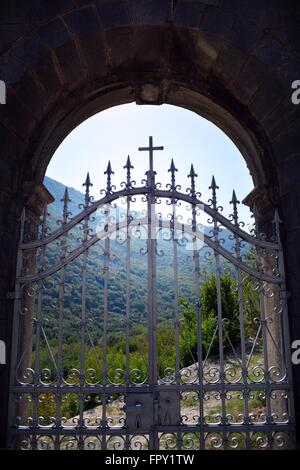 Sur la montagne vue à travers l'église, la porte en fer forgé peint argent, dans Morinje, baie de Kotor au Monténégro Banque D'Images