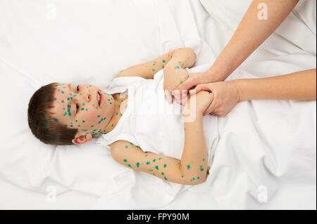 Enfant malade au lit a le virus sur la peau, mother's main touche le front Banque D'Images