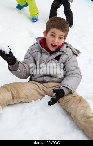 Close up enfant assis sur la neige boule de traction Banque D'Images