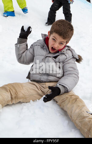 Close up enfant assis sur la neige boule de traction Banque D'Images