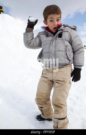 Close up enfant assis sur la neige boule de traction Banque D'Images