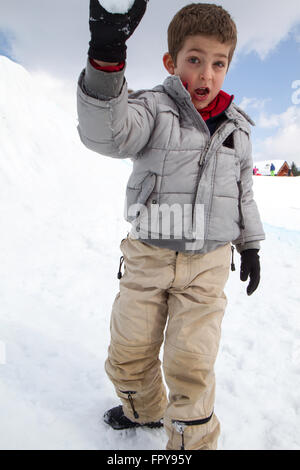 Close up enfant assis sur la neige boule de traction Banque D'Images