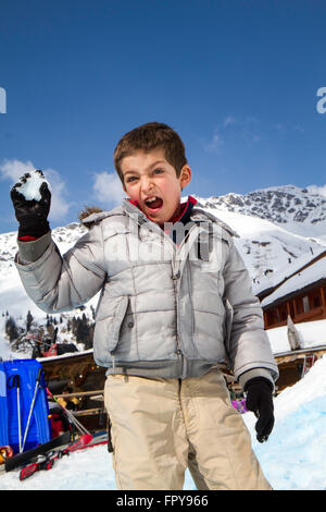 Close up enfant tirant snowball avec fond de ciel bleu Banque D'Images