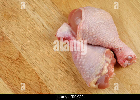 Cuisses de poulet frais ou pilons de poulet sur une planche à découper - close up Banque D'Images