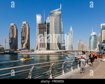 Les gens qui marchent sur la promenade, les bateaux et les tours d'habitation dans le quartier du port de plaisance de Dubaï, Émirats Arabes Unis Banque D'Images