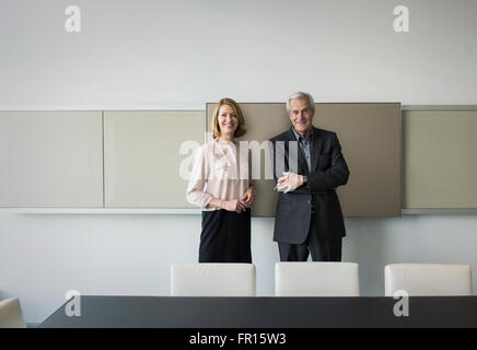 Portrait confiant businessman and businesswoman in conference room Banque D'Images