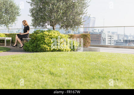 Businesswoman working on urban rooftop garden Banque D'Images