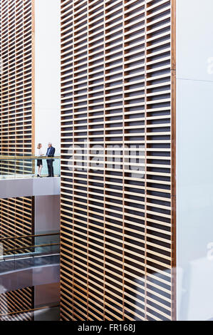 Business people talking on walkway in modern office atrium Banque D'Images