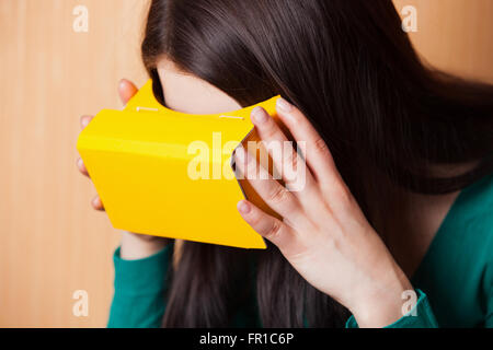 Portrait of a Girl wearing carton casque de réalité augmentée avec son téléphone intelligent. Banque D'Images