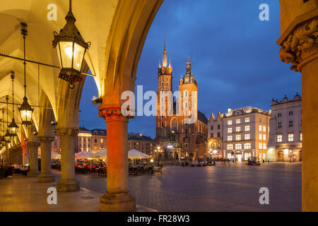 La nuit tombe sur la place du marché principale de Cracovie, Pologne. À la recherche de la Halle aux Draps vers l'église St Mary. Banque D'Images