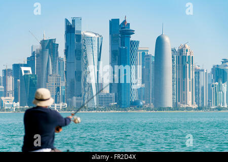 La pêche sur l'homme de front de mer Corniche en direction de tours de bureaux modernes à West Bay, quartier financier et d'affaires à Doha Qatar Banque D'Images