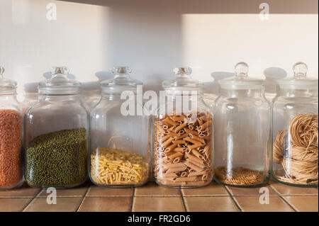 Rangée de grands bocaux en verre cuisine dans une rangée avec les lentilles vertes rouge coquilles de pâtes et tagatelli Banque D'Images