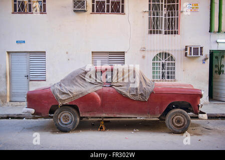 Une voiture rouge vintage dans le besoin de quelques réparations sur les rues de la Vieille Havane, Cuba. Banque D'Images