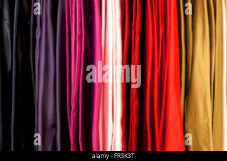 Arrière-plan flou de tissu de différentes couleurs, est suspendu un rack dans un magasin. Banque D'Images
