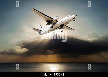 Avion avec sunbeam et nuage tempête sur mer en plus de la lumière du soleil, de tons sombres Banque D'Images