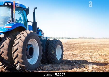 Tracteur bleu sur l'arrière-plan d'un champ vide et un ciel bleu clair Banque D'Images