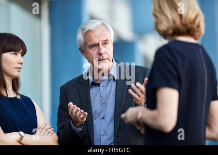 Senior businessman gesturing et parler aux collègues Banque D'Images