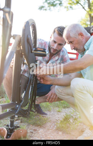 Père et fils adultes réparation chaîne de vélo Banque D'Images