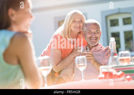 Senior couple smiling et boire du vin sur un patio ensoleillé Banque D'Images