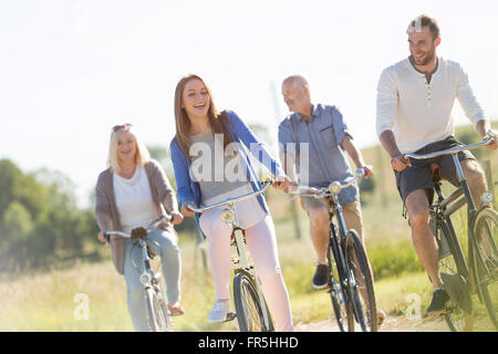 Famille heureuse l'équitation de vélo sous le soleil de domaine Banque D'Images