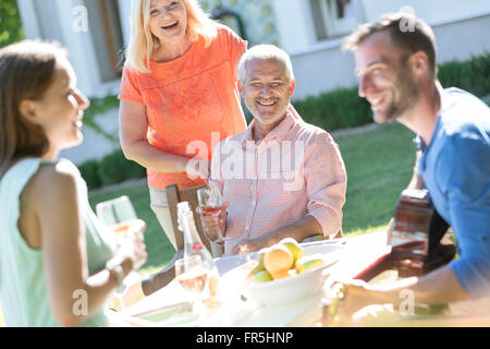 Famille de boire du vin et à jouer de la guitare à table de patio ensoleillé Banque D'Images