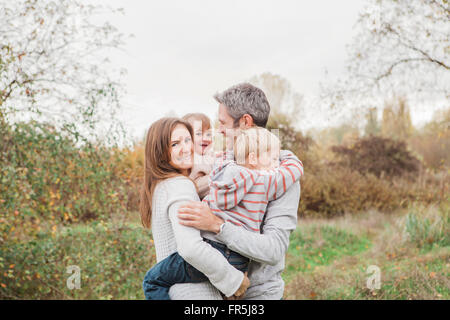 Smiling family hugging in autumn park Banque D'Images