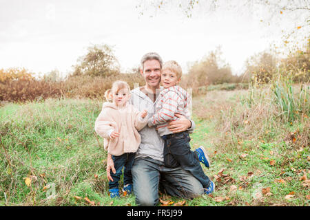 Portrait smiling père et les tout-petits enfants dans le parc en automne Banque D'Images