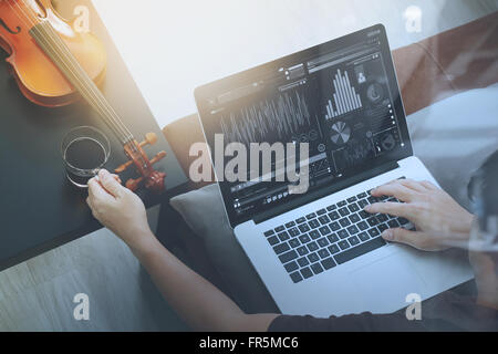 Hipster part composer de la musique avec ordinateur portable compter et sitting on sofa at home studio Banque D'Images