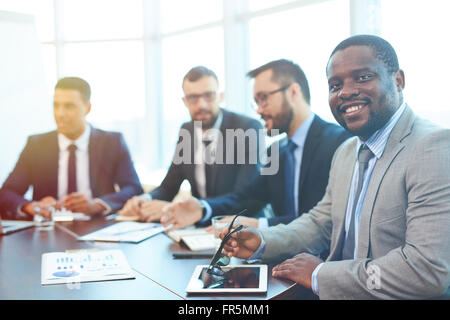 Smiling African businessman sitting at réunion avec ses collègues Banque D'Images