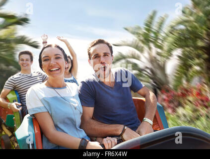 Jeune couple acclamant amusement park ride Banque D'Images