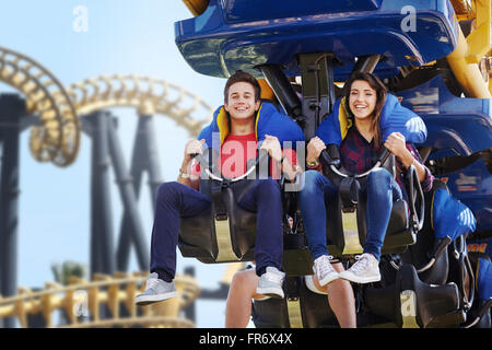 Jeune couple riding amusement park ride Banque D'Images