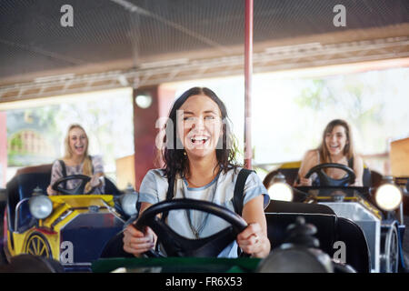 Portrait of smiling young woman riding voitures de butoir à amusement park Banque D'Images