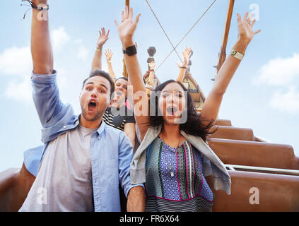 Portrait d'amis enthousiastes acclamant amusement park ride Banque D'Images