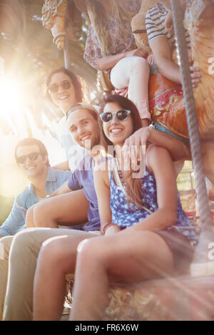 Portrait smiling friends at amusement park carousel Banque D'Images