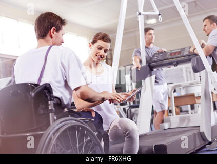 Thérapeute physique montrant digital tablet à l'homme en fauteuil roulant Banque D'Images