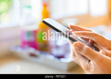 Mains Gros plan femme à l'aide d'un téléphone mobile, la maison. Sms, sms, message, mail, app Banque D'Images