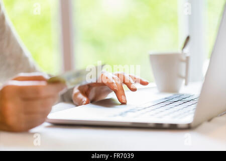 Femme à l'intérieur à l'aide de carte de crédit et d'ordinateur portable. Achats en ligne. Jardin d'arrière-plan flou Banque D'Images