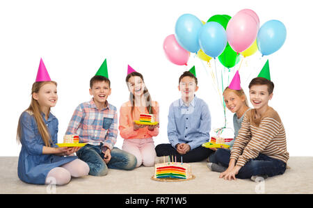 Heureux les enfants en chapeaux de fête avec gâteau d'anniversaire Banque D'Images