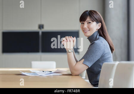 Portrait confident businesswoman with paperwork in conference room Banque D'Images