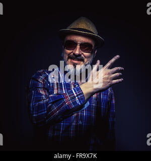 Portrait d'un homme d'âge moyen avec chapeau et chemise à carreaux, montrant quelque chose. Banque D'Images