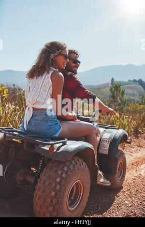 Portrait de jeune homme et femme dans la nature sur un véhicule hors route. Jeune couple bénéficiant d'un quad bike ride en campagne. Banque D'Images