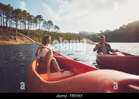 Jeune couple kayak sur un lac. Les jeunes pratiquants de l'aviron sur le lac sur journée d'été. Banque D'Images