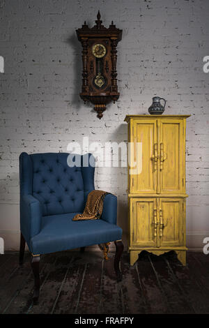 Still Life of vintage fauteuil bleu, jaune placard, horloge à pendule et orange écharpe ornée en studio Banque D'Images