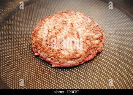 Un burger de boeuf maigre friture dans une casserole Banque D'Images