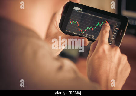 Un homme contrôle de stock market sur smartphone Banque D'Images