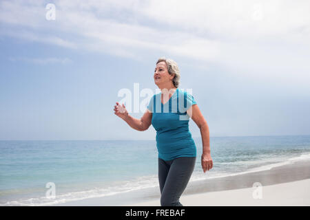 Senior woman jogging sur la plage Banque D'Images